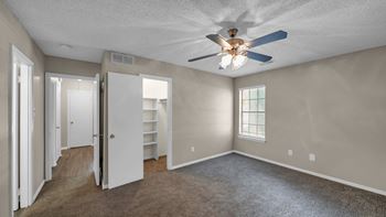 A room with a ceiling fan and a window with blinds.